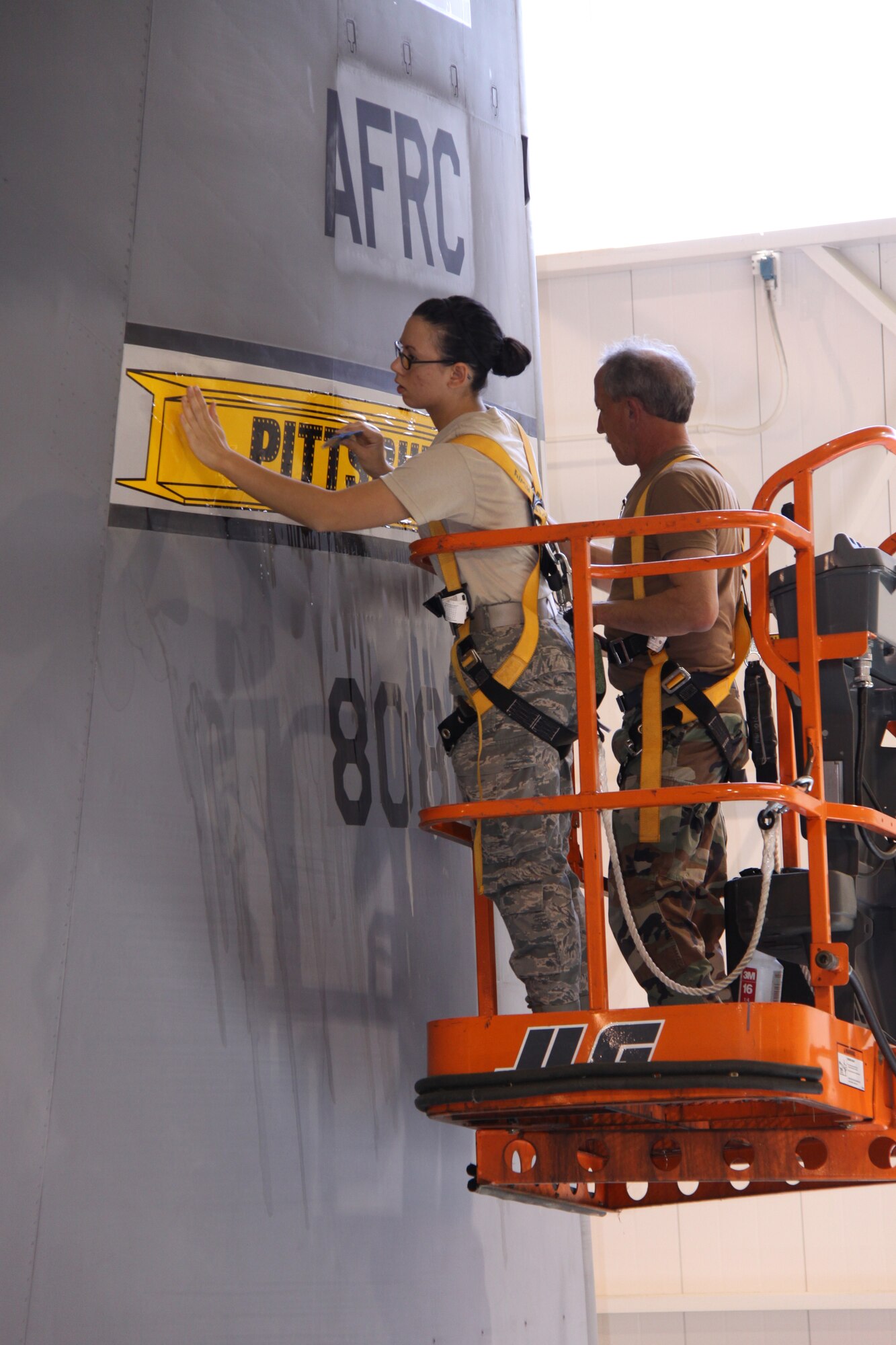 Airman Ashley Wiley, 911th Aircraft Maintenance Squadron, and Master Sgt. Mark Finney, 911th Maintenance Squadron put the finishing touches on the first C-130 to receive the new tail flashing.  The steel beam represents the strong bond the 911th Airlift Wing has with the community of Pittsburgh and recognizes the city’s rich heritage.