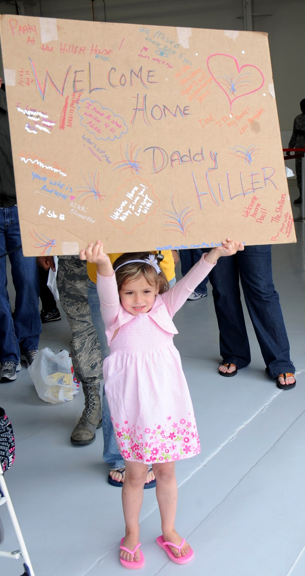 Isabella Hiller holds a sign for her father during a welcome home at Cannon Air Force Base May 8. Operation Homecoming greeted Cannon Airmen back from overseas deployments.  Base Personnel were welcomed back by friends and family with snacks and music. (U.S. Air Force Photo by Senior Airman Evelyn Chavez)