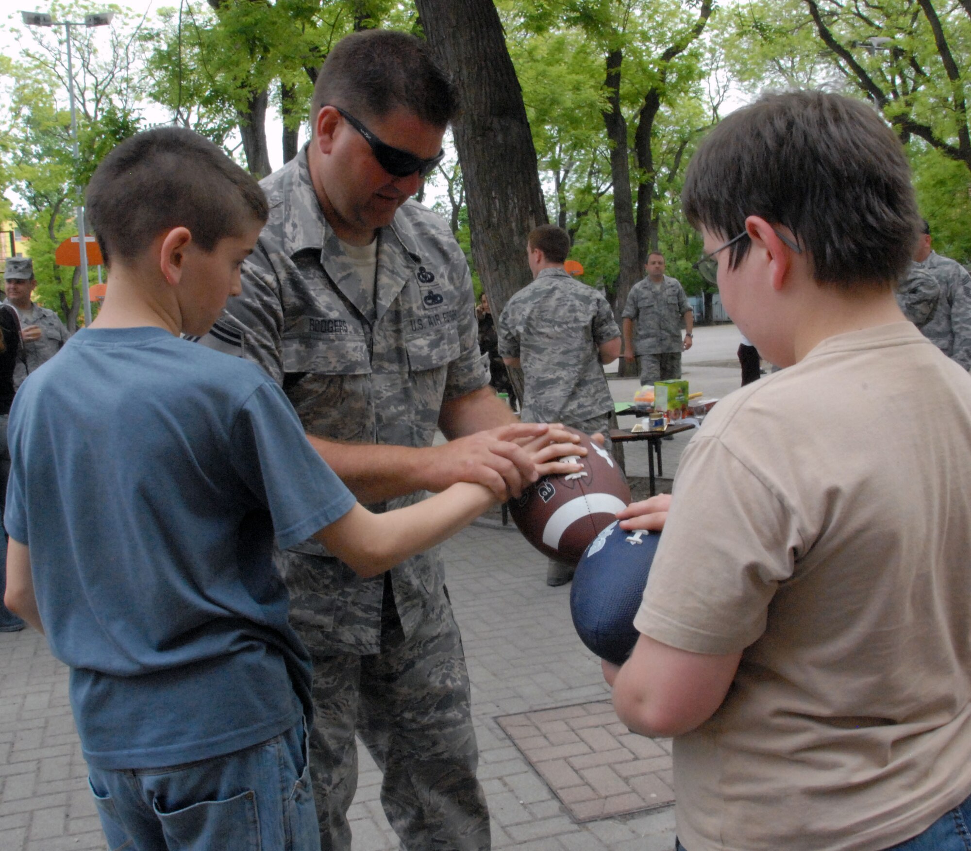 KECSKEMET, Hungary -- Senior Master Sgt. Curt Rodgers, 178th Fighter Wing safety NCO,  demonstrates the proper way to hold an American Football to children at Peace's Square Elementary School, a low-income school in Kecskemet, Hungary May 5. The 178F W Guardsmen, currently in Hungary for the Load Diffuser Exercise 2010, raised money to donate items to two local schools.