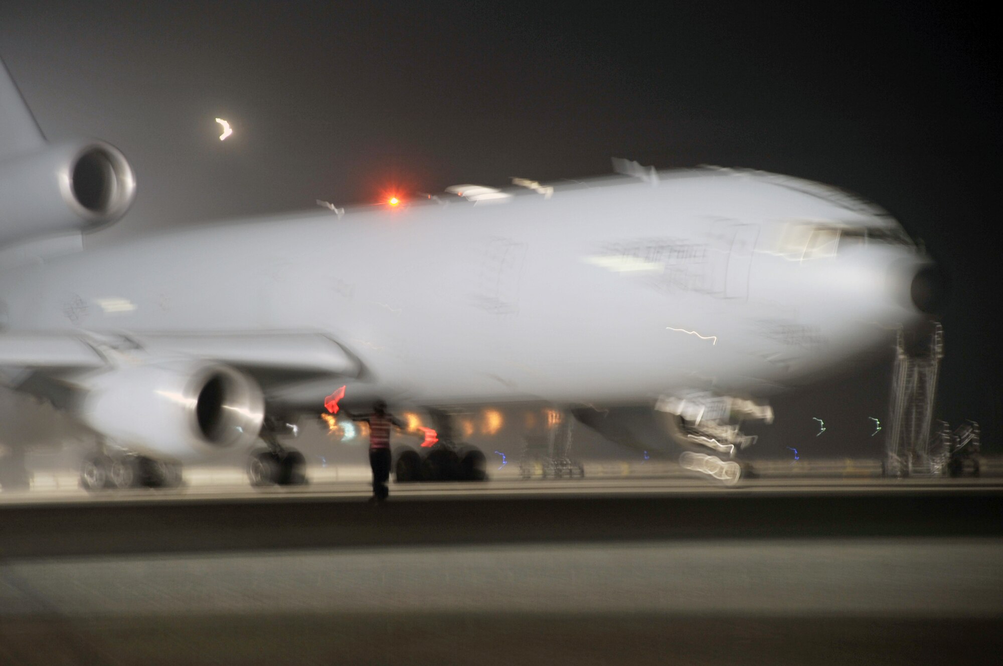 A KC-10 Extender maintenance Airman from the 380th Expeditionary Aircraft Maintenance Squadron Extender aircraft maintenance unit uses light sticks to help guide aircrew members driving a KC-10 for a mission April 30, 2010, at a non-disclosed base in Southwest Asia. The 380th EAMXS, as part of the 380th Air Expeditionary Wing, supports operations Iraqi Freedom and Enduring Freedom and the Combined Joint Task Force-Horn of Africa. (U.S. Air Force Photo/Master Sgt. Scott T. Sturkol/Released)