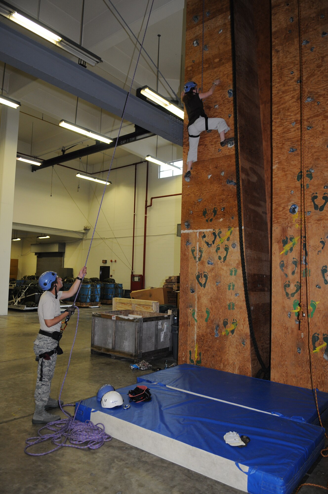 KADENA AIR BASE, Japan -- Eileen O'Reilly climbs a rock-climbing training wall as Staff Sgt. Kevin Freyre, a 320th Special Tactics Squadron pararescueman, supports her here May 7 during a spouse orientation day. Spouses from the 353rd Special Operations Group were treated to a small capabilities brief, a tour of the 320th Special Tactics Squadron and their equipment and orientation flights on a MC-130P Combat Shadow and MC-130H Combat Talon II during the event. (U.S. Air Force photo by Tech. Sgt. Aaron Cram)