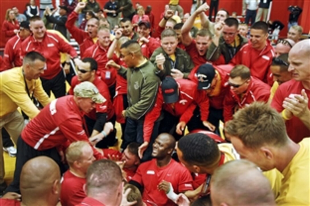 Teammates and fans pile on Marine Corps Gunnery Sgt. Marcus Wilson, center, after a nail-biting victory over Team Army-3 in sitting volleyball at the U.S. Olympic Training Center in Colorado Springs, Colo., May 11, 2010. The Marines defeated the Army 2-0 in a best-of-three match in the preliminary round of the inaugural Warrior Games' sitting volleyball pool play. The games run through May 14 and features some 200 wounded warriors and disabled veterans in paralympic-type competition.