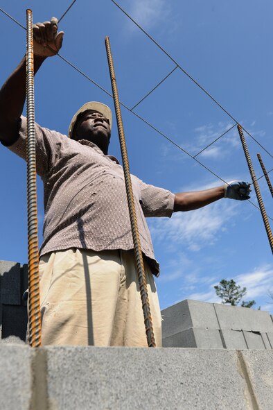MOODY AIR FORCE BASE, Ga. -- Frank Flucas, contract worker, slides wire into position before placing cinder blocks into place during construction on the Combat Arms Training and Maintenance site here May 10. The wire is used as extra stability for the cinder blocks to stay in place. (U.S. Air Force photo by Airman 1st Class Benjamin Wiseman/RELEASED)