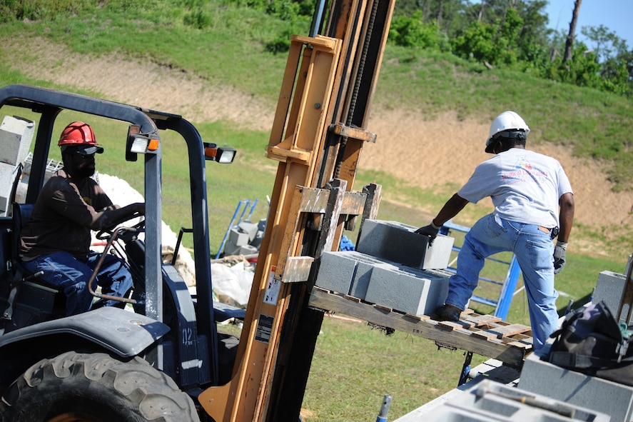 MOODY AIR FORCE BASE, Ga. -- Herbert Amos, contract worker, raises a pallet of cinder blocks to Gerald Stacks, contract worker, here May 10. Mr. Amos and Mr. Stacks are working to build a dividing wall between the outdoor range and indoor range at the Combat Arms Training and Maintenance site. (U.S. Air Force photo by Airman 1st Class Benjamin Wiseman/RELEASED)