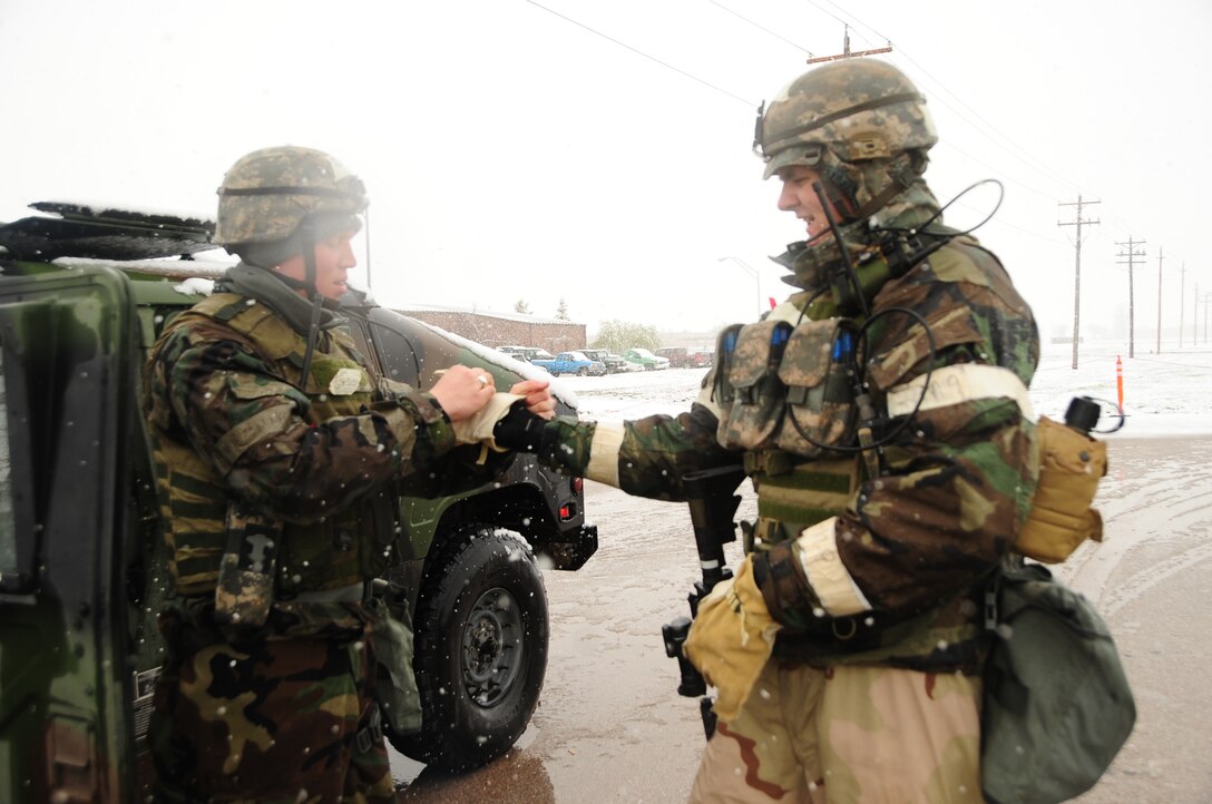 ELLSWORTH AIR FORCE BASE, S.D. – (Left) Senior Airman Michael Owyen, 28th Security Forces Squadron patrolman, assists Senior Airman Jeremy Ross, 28 SFS patrolman, with putting on warm gloves during a Phase II Operational Readiness Exercise, May 12.  Airmen took steps to ensure proper safety and protection from the snow during the exercise. (U.S. Air Force photo/Airman 1st Class Anthony Sanchelli)