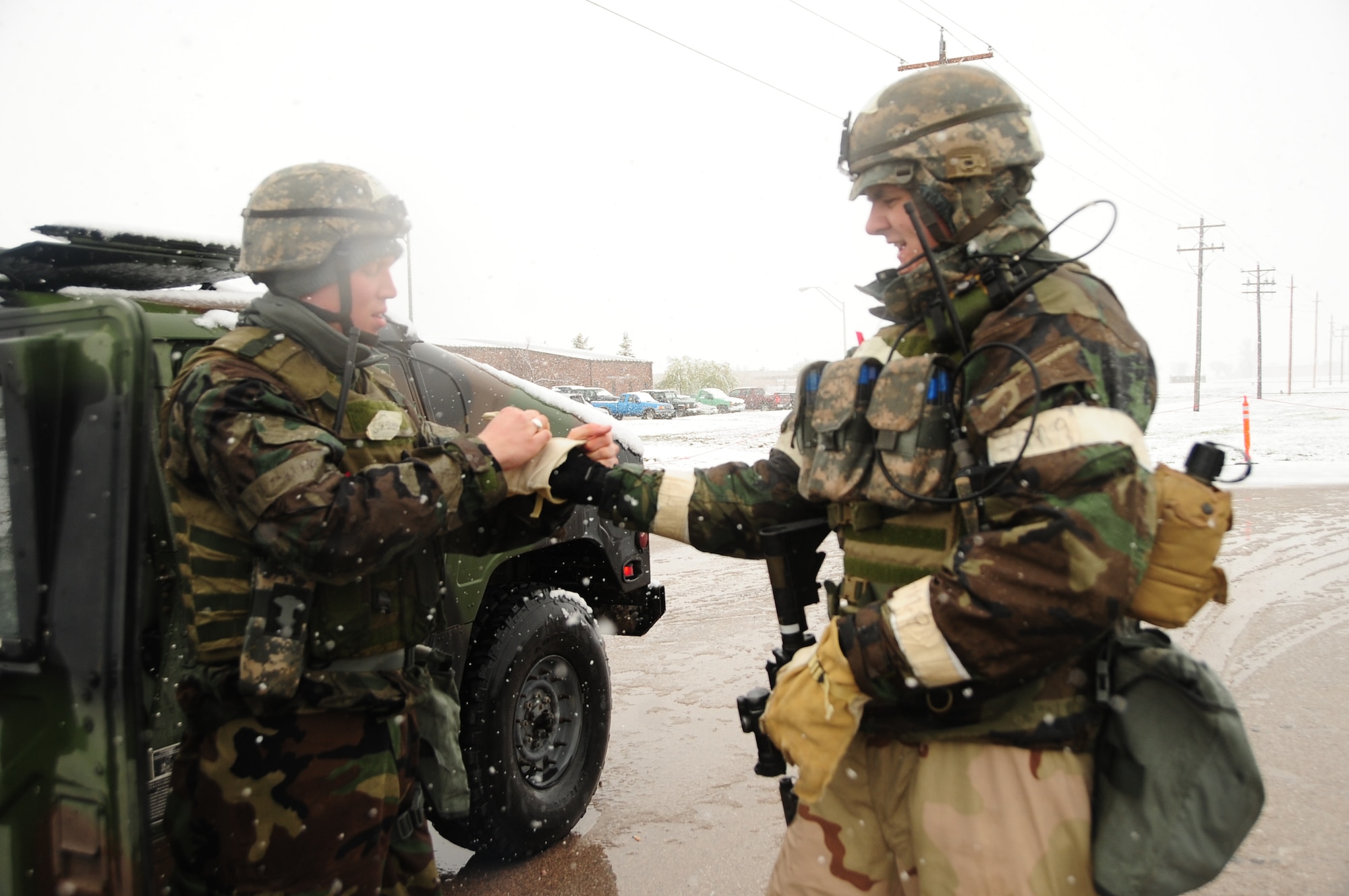 ELLSWORTH AIR FORCE BASE, S.D. – (Left) Senior Airman Michael Owyen, 28th Security Forces Squadron patrolman, assists Senior Airman Jeremy Ross, 28 SFS patrolman, with putting on warm gloves during a Phase II Operational Readiness Exercise, May 12.  Airmen took steps to ensure proper safety and protection from the snow during the exercise. (U.S. Air Force photo/Airman 1st Class Anthony Sanchelli)