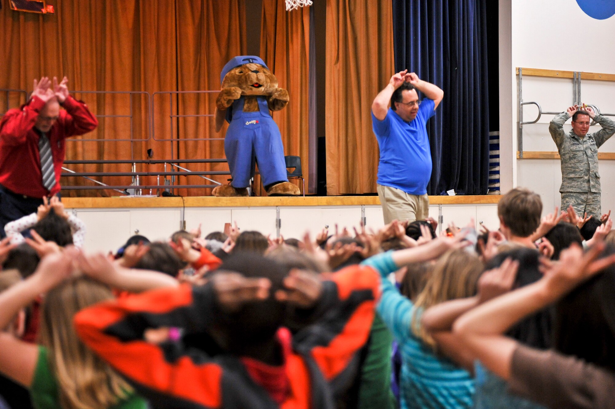 ELMENDORF AIR FORCE BASE, Alaska – Bob Hill, left, Sam Renick, middle, Lt. Col. Michael Strunk, 3rd Mission Support Group, right, and Sammy the Rabbit, stage, sing along with a gymnasium full of Aurora Elementary School children May 12. Mr. Renick has traveled the globe with his pal Sammy the Rabbit, teaching children it’s important to save money through his books and songs. During his first trip to Alaska, Mr. Renick visited all three Elmendorf Elementary Schools. (Air Force photo by Airman 1st Class Christopher Gross)