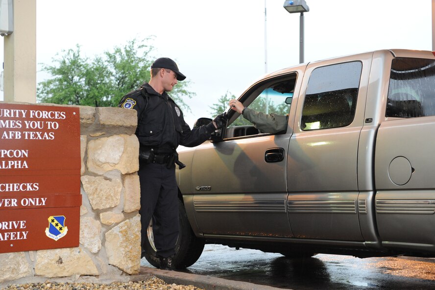 DYESS AIR FORCE BASE, Texas—Adam Keidl Jr., U.S. Protect employee, checks identification cards May 13 at the front gate here. The mission to keep Dyess safe does not stop because of weather. Employees from the U.S. Protect agency work with the 7th Security Forces Squadron securing the base 24/7 through rain, snow, heat and all kinds of weather. (U.S Air Force photo/Airman 1st Class Shannon Hall)