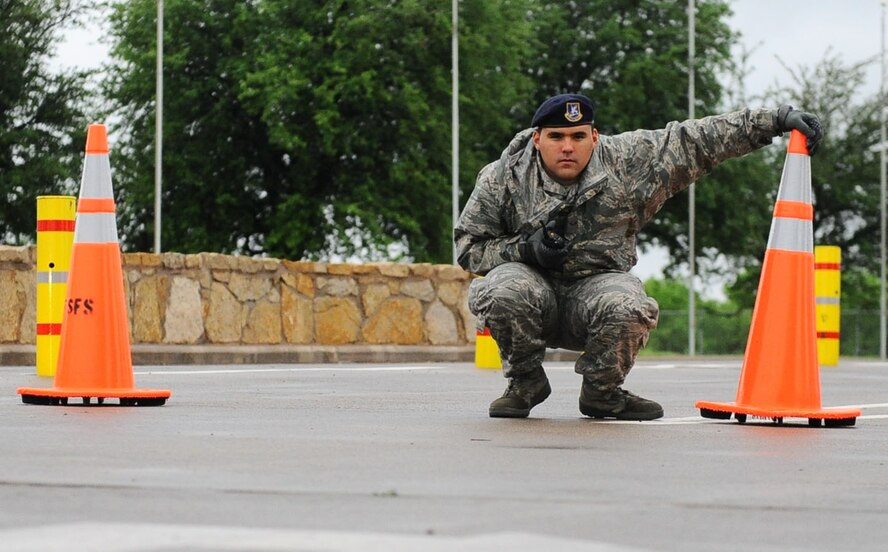 DYESS AIR FORCE BASE, Texas—Airman 1st Class Nicholas Navarro, 7th Security Forces Squadron, squats low to get a better view of the distant approaching ambulance May 13 at the main gate here.  Airman Navarro was responsible for clearing the pathway for the emergency vehicle in the cold and rainy weather.  Members of the 7 SFS endure foul weather while enforcing security at various different posts on the installation. (U.S. Air Force photo/ Senior Airman Domonique Washington)