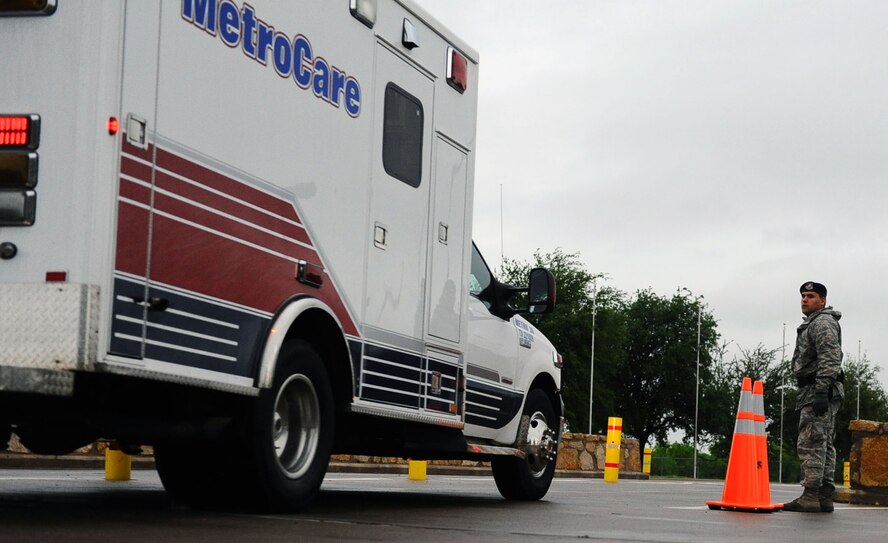 DYESS AIR FORCE BASE, Texas—Airman 1st Class Nicholas Navarro, 7th Security Forces Squadron,  removes safety cones to open the lane for an emergency response vehicle May 13  coming through the main gate here.  Airman Navarro awaited the arrival of the ambulance in the cold, wet weather and communicated through radio to confirm the ambulances arrival. Many 7 SFS members enforce security measures on the installation through adverse weather conditions.  (U.S. Air Force photo/ Senior Airman Domonique Washington)