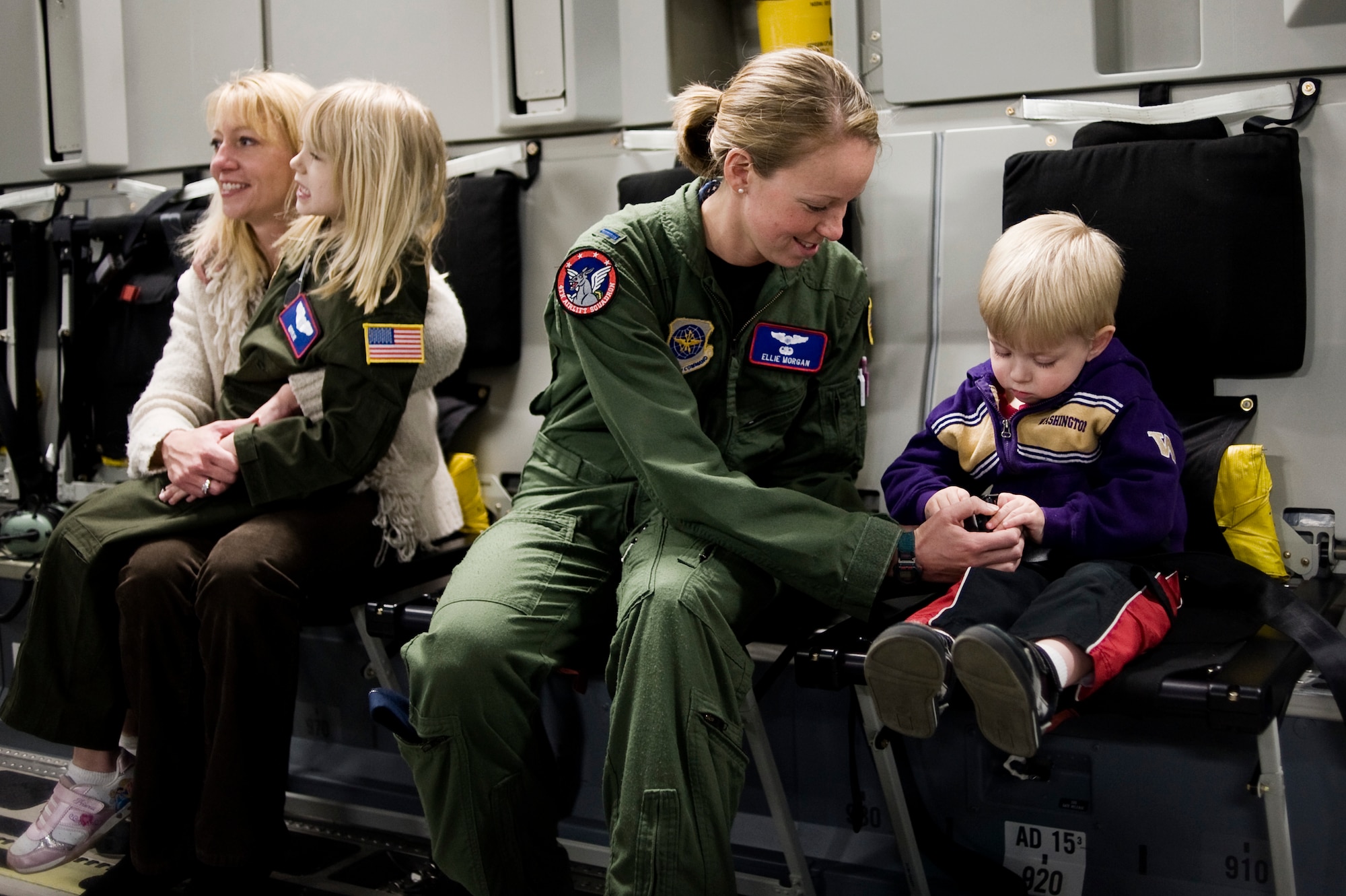 1st Lt. Ellie Morgan, 4th Airlift Squadron, center, assists Kaylie Bergen, 6, and brother Dylan, 3, with seatbelts in preparation for a photo-op onboard a C-17 Globemaster III May 11. (U.S. Air Force Photo by Abner Guzman)

