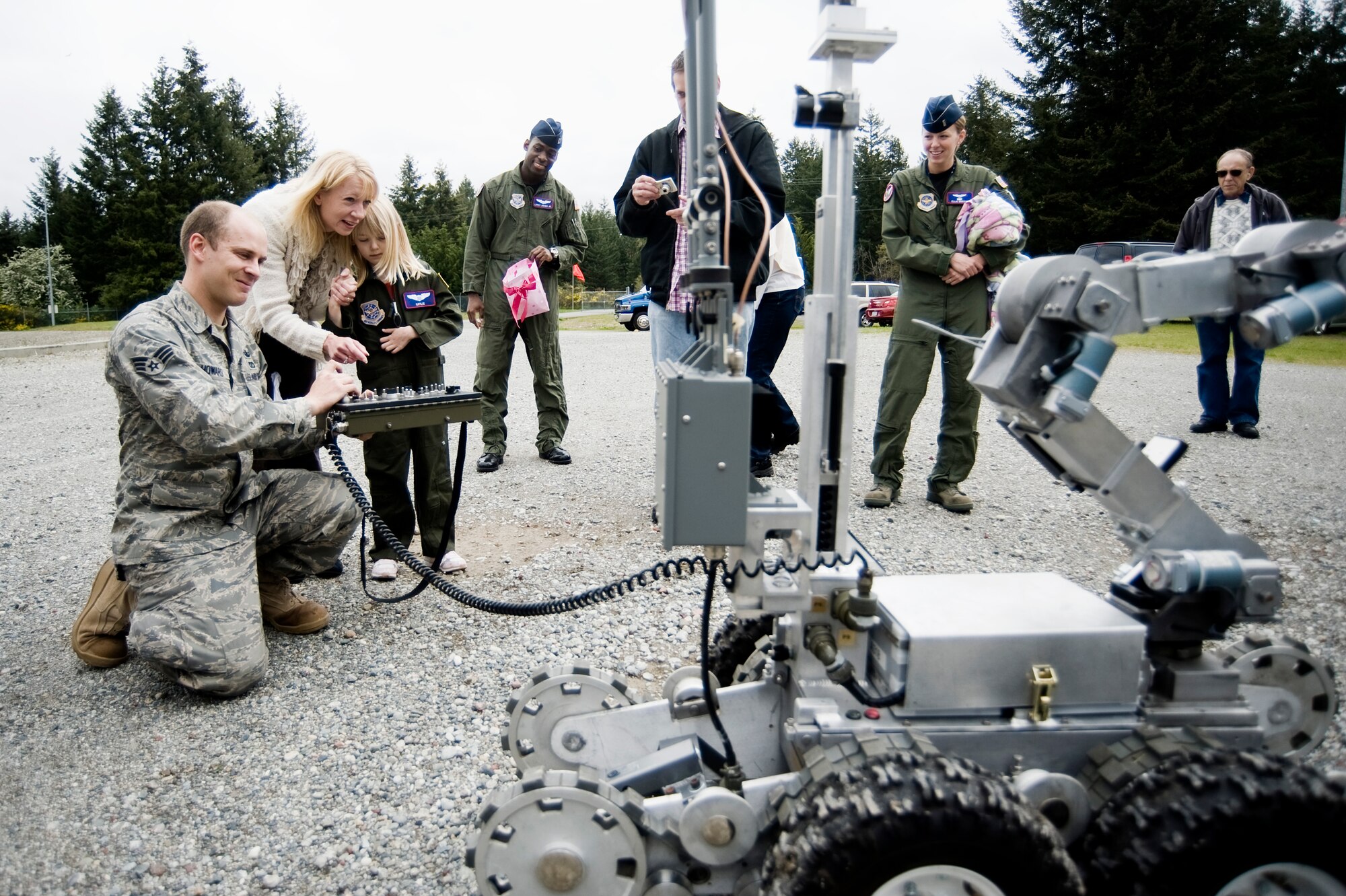 Pilot for a Day candidate Kaylie Bergen, age 6, and her family look on as Senior Airman Nathan Howard, 62nd Civil Engineer Squadron, demonstrates the capabilities of an EOD robot May 11. (U.S. Air Force Photo by Abner Guzman)
