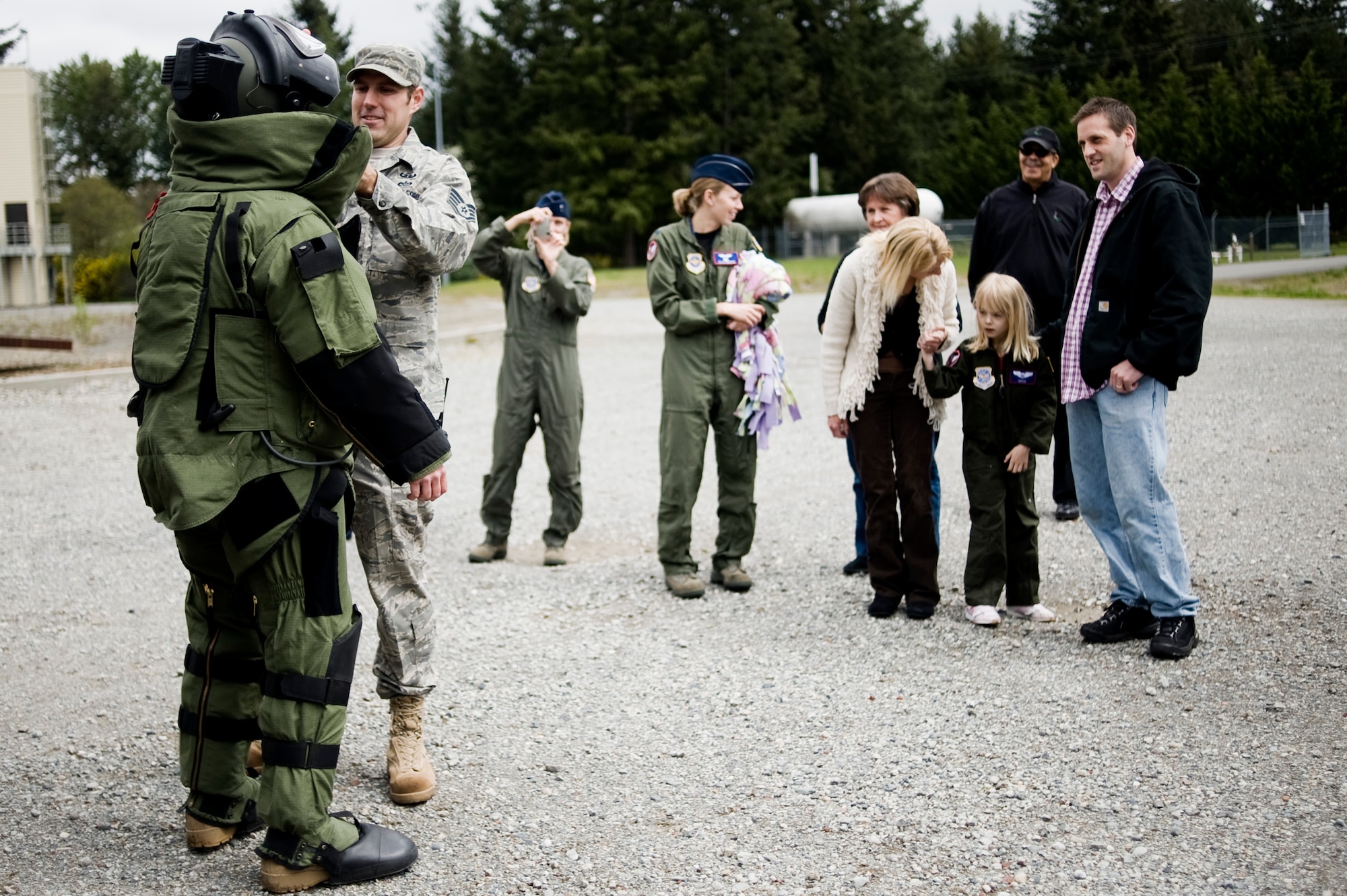 Pilot for a Day candidate Kaylie Bergen, age 6, and her family look on as Staff Sgt. Mark Walker and Airman 1st Class Mark Stafford, 62nd Civil Engineer Squadron, demonstrate the capabilities of an EOD protective bomb suit May 11. (U.S. Air Force Photo by Abner Guzman)


