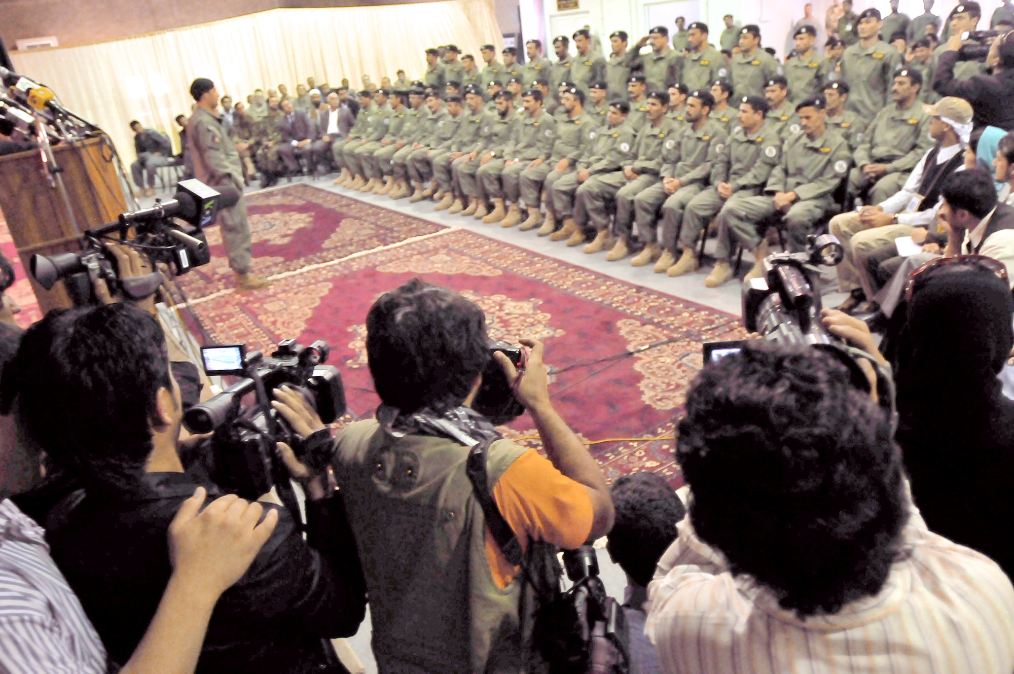 Afghan soldiers listen to speeches and are photographed by local and international press during a transition ceremony May 5, 2010, at a conference center on the Afghan National Army Air Corps base in Kabul, Afghanistan. The soldiers are from the Ministry of Interiors Air Interdiction Unit. (U.S. Navy photo/Petty Officer 2nd Class David Quillen)