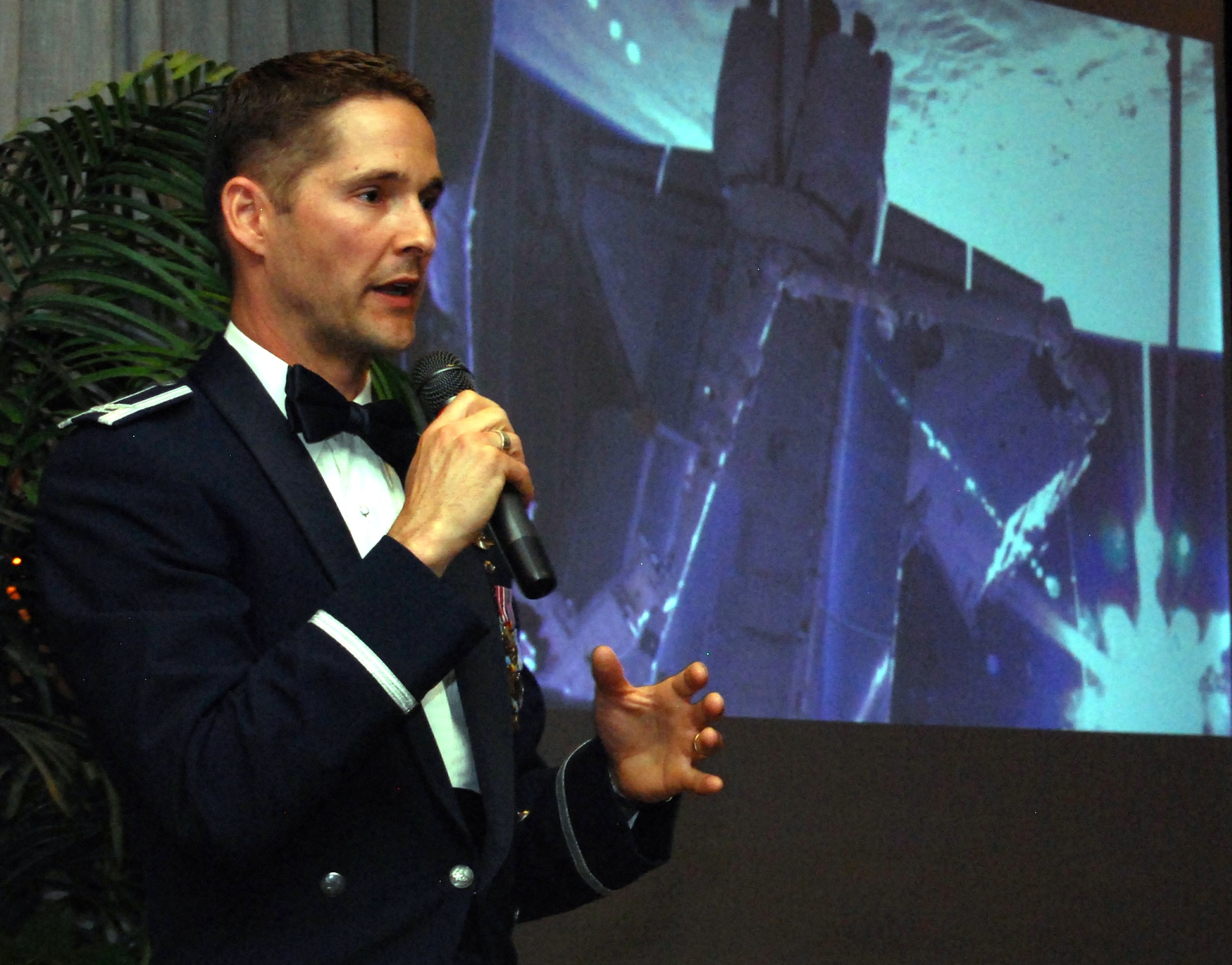 Col. Jim Dutton narrates a video compilation of the STS-131 space shuttle mission during a Department of Astronautics dining-out at the Air Force Academy's Falcon Club May 7, 2010. Colonel Dutton, a 1991 Academy graduate and astronautics major, was the pilot for the mission in April to install a robotics laboratory on the International Space Station. (U.S. Air Force photo/Staff Sgt. Don Branum)