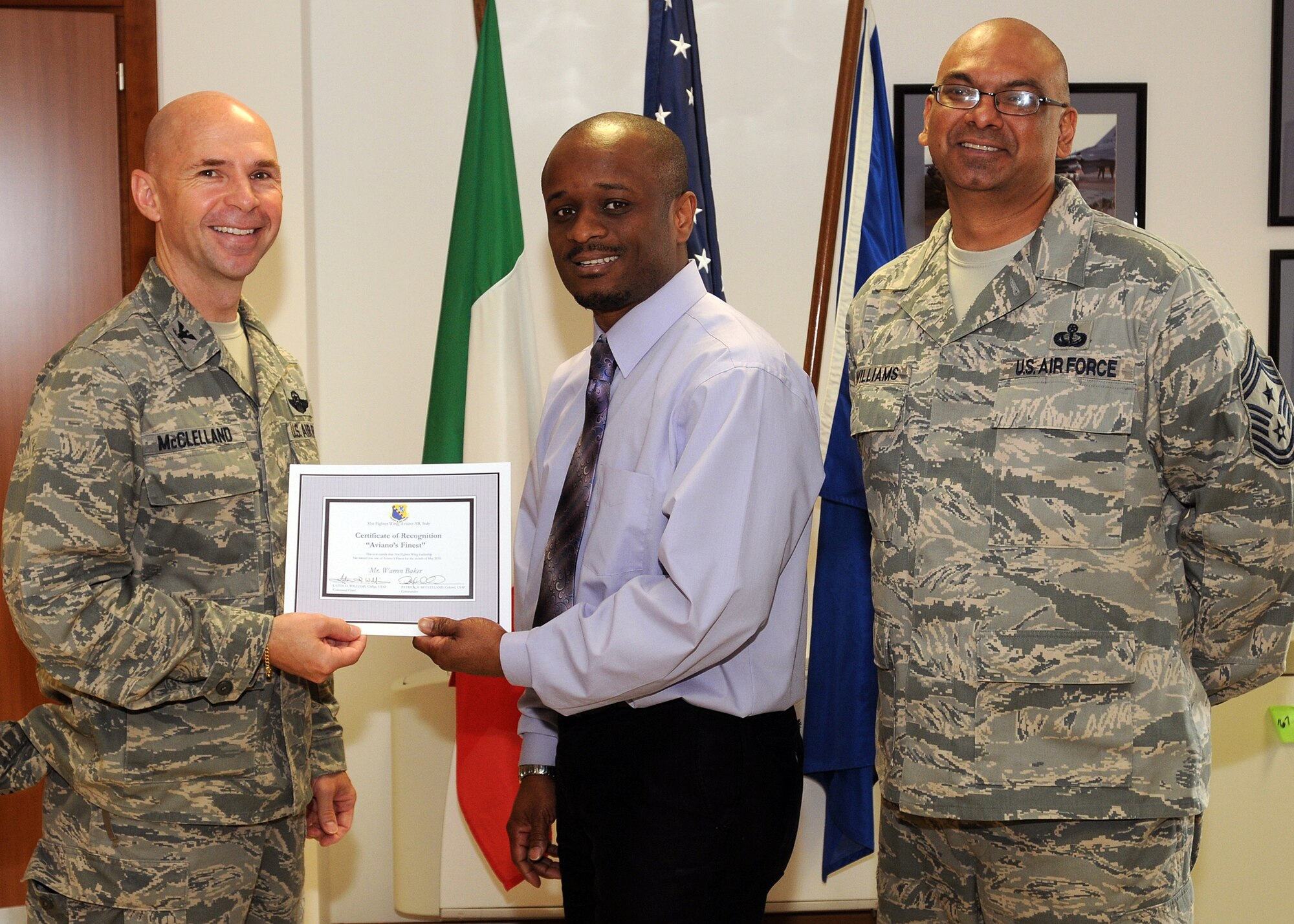 Col. Patrick A. McClelland, 31st Fighter Wing vice commander, congratulates Mr. Warren Baker, 31st Operations Group administrative clerk, on his selection as one of Aviano's Finest as Chief Master Sgt. Laten Williams, 31st FW command chief, looks on. (U.S. Air Force photo/ Senior Airman Tabitha M. Mans)