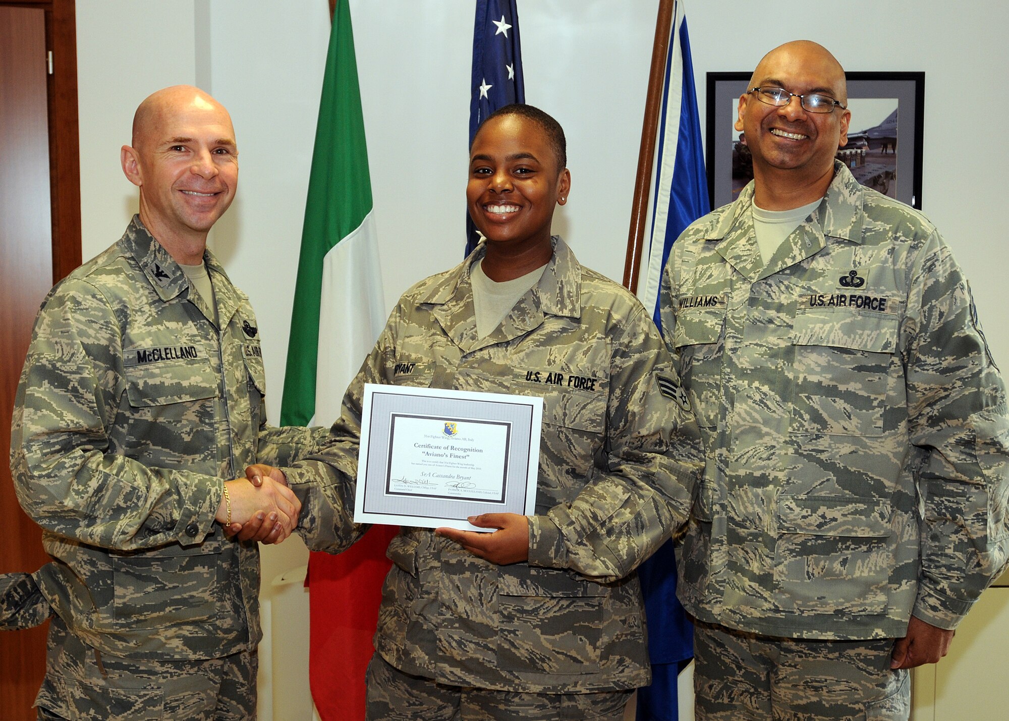 Col. Patrick A. McClelland, 31st Fighter Wing vice commander, congratulates Senior Airman Cassandra Bryant, 31st Operations Group knowledge operator, on her selection as one of Aviano's Finest as Chief Master Sgt. Laten Williams, 31st FW command chief, looks on. (U.S. Air Force photo/ Senior Airman Tabitha M. Mans)