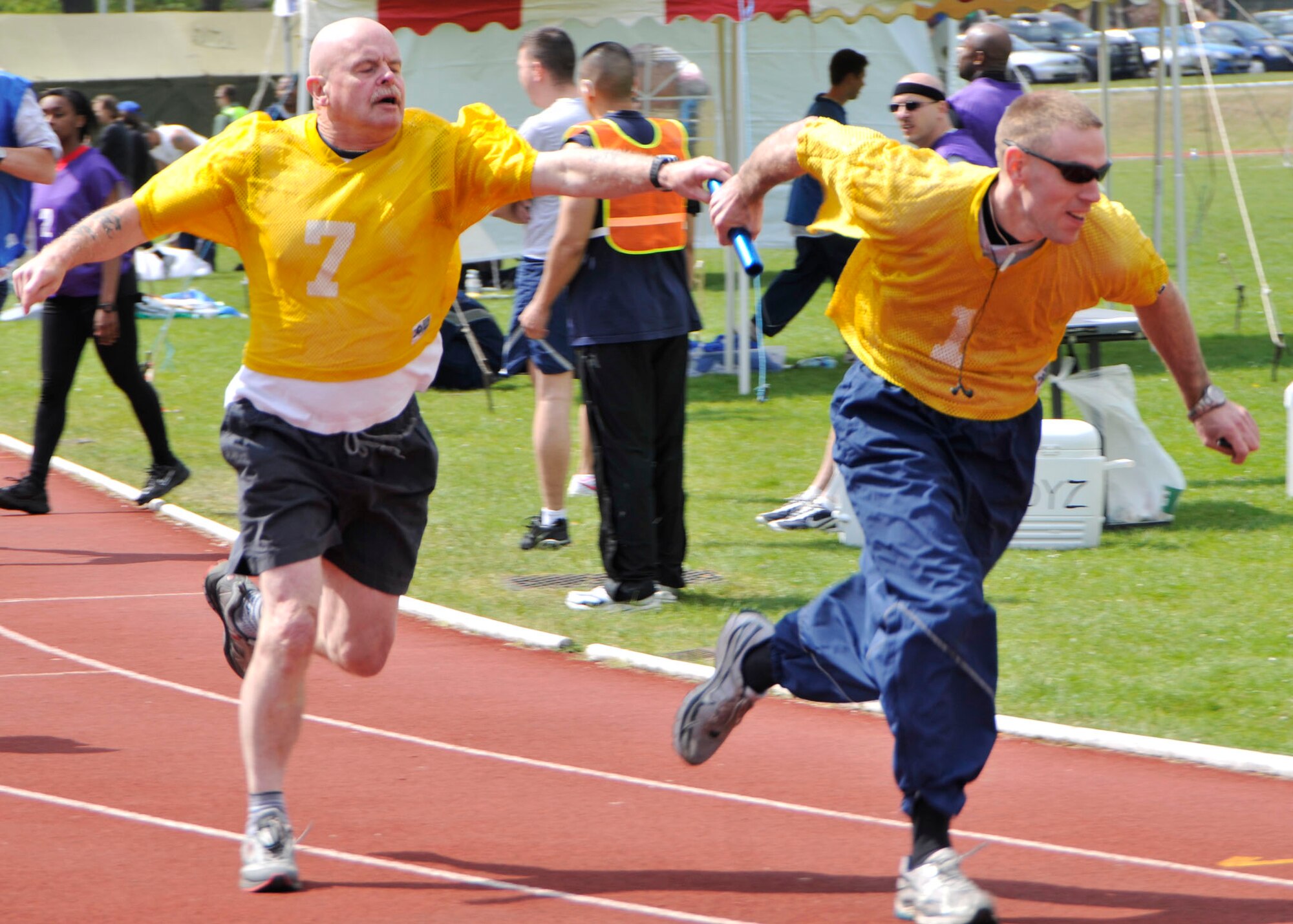 Bernie Prior, 48th Logistics Readiness Squadron receiving supervisor, seamlessly passes the baton to fellow LRS member Airman 1st Class Scott Knight an air transportation apprentice, during the 8-Hour Squadron Run at the RAF Lakenheath track May 7. (U.S. Air Force photo/Airman 1st Class Tiffany M. Deuel)