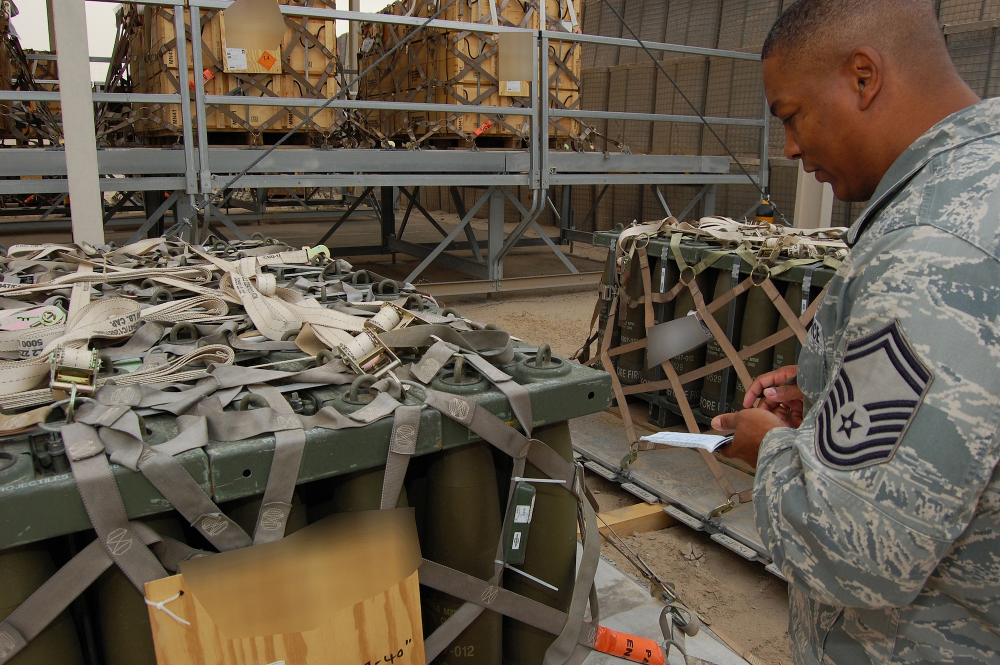 U.S. Air Force Senior Master Sgt. Gilbert Edwards, 386th Air Expeditionary Wing Weapons Safety manager, conducts a weapons safety inspection on 105 mm projectiles due to deploy downrange May 12, 2010 at an air base in Southwest Asia. Sergeant Edwards conducts periodic sampling inspections of munitons to ensure cargo is safe to travel on awaiting aircraft. (U.S. Air Force photo illustration by Staff Sgt. Lakisha A. Croley/Released)