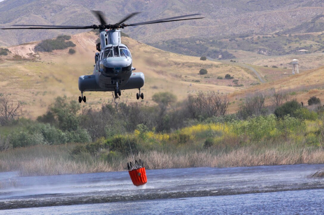 A CH-46 Sea Knight helicopter from 3rd Marine Air Wing, Marine Corps Air Station Miramar, fills its 320-gallon bucket with water from Las Pulgas Lake during the third annual aerial firefighting effort at Camp Pendleton, May 13. Approximately 34 emergency service personnel and several aircraft from Marine Corps Base Camp Pendleton, Marine Corps Air Station Miramar, Naval Air Station North Island and California’s Department of Fire and Forestry Protection (CAL FIRE) extinguished simulated fires on base by coordinating helicopter water drops.