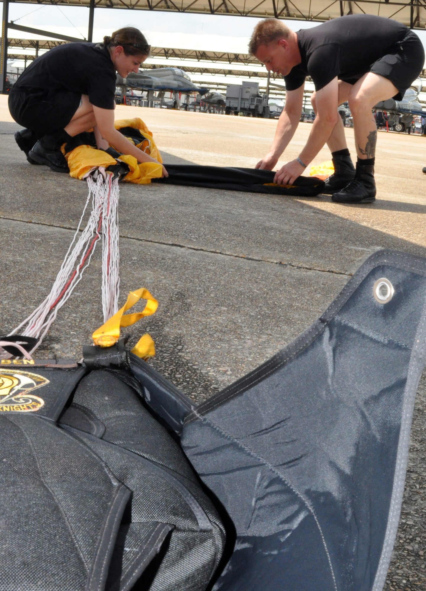 Army Sgt. Jennifer Schaben and Sgt.1st Class John Berentis pack a parachute with a U.S. Army flag prior to a practice demonstration jump May 14. Sergeants Schaben and Berentis are members of the U.S. Army Golden Knights Parachute Demonstration Team and are taking part in Wings over Columbus 2010. (U.S. Air Force photo/Senior Airman Jacob Corbin)