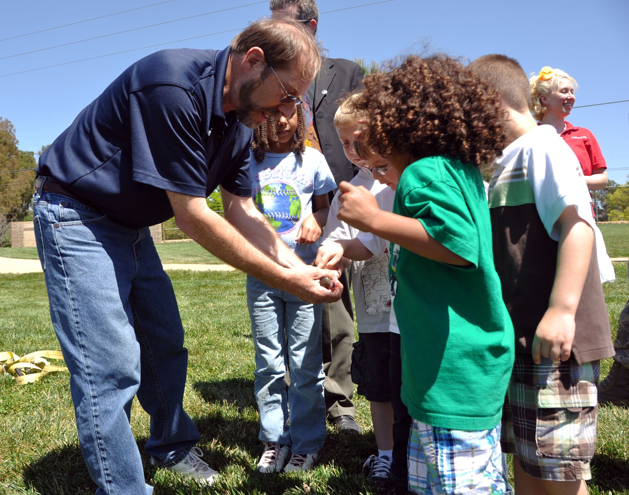 An employee of a local fishery company shows children from local Travis elementary schools a fish before releasing it into the Duck Pond May 6.  Approximately 800 bass were released into the pond in preparation for the Kids Day of Fishing event that took place May 8. (U.S. Air Force photo/Senior Airman Kristen Rohrer)