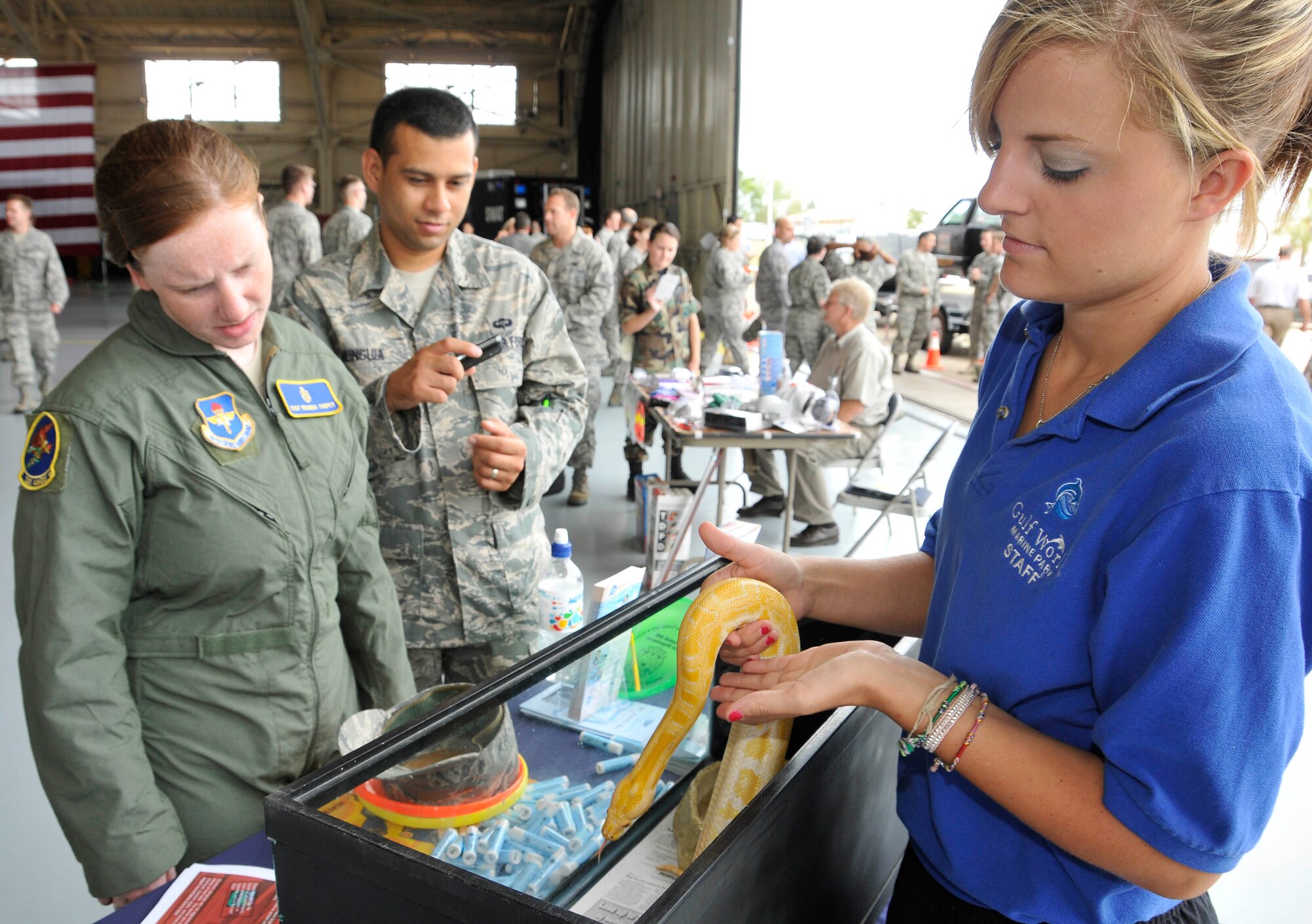 Two Tyndall Airmen look on as a Gulf World employee handles and describes a python May 14 at the Safety Day Fair in Hangar One. (U.S. Air Force photo by Lisa Norman)