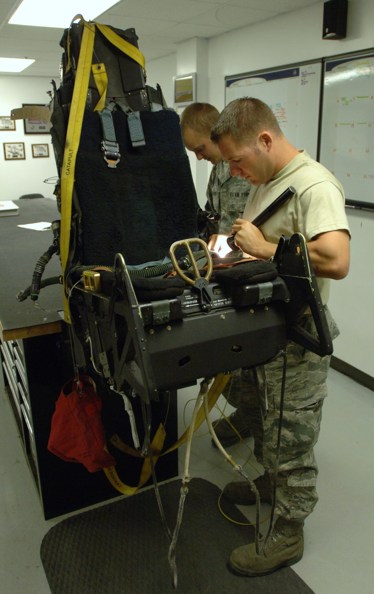 LANGLEY AIR FORCE BASE, Va. -- Staff Sgt. Ronald Kavanaugh, 192d Fighter Wing egress technician, and Airman 1st Class William Stanton, 1st Component Maintenance Squadron egress apprentice, inspect an Advanced Concept Ejection Seat II ejection system from an F-22 Raptor May 12. Each system undergoes an egress final inspection every 30 days, in which technicians physically inspect every component of the system they can touch. (U.S. Air Force photo/Airman 1st Class Jason J. Brown)