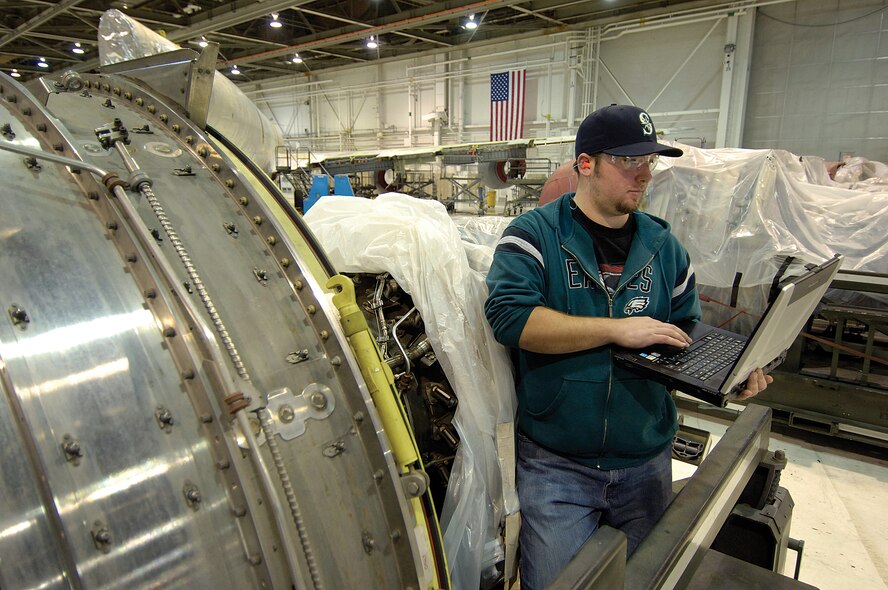 Mechanic Dan Maiso gets up-to-date technical order information on a laptop computer at his side on the depot floor of Bldg. 3001.  Relying on a paper technical order or a wired computer to get information crucial to repairing aircraft and engines, such as this F108, are evolving to portable, wireless computers that can be updated as needed and carried by the mechanics to their work. (Air Force photo by Margo Wright)