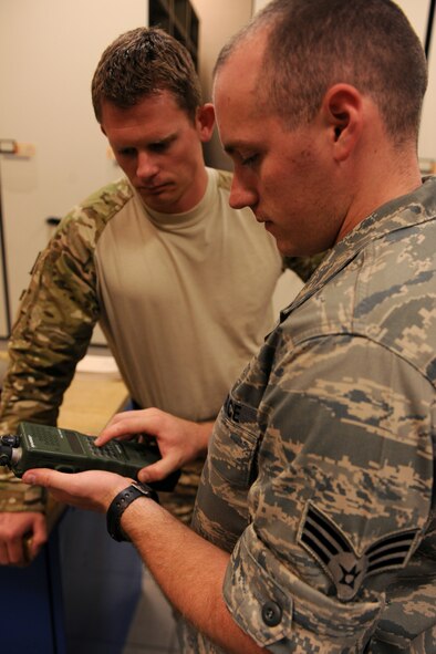 MOODY AIR FORCE BASE, Ga. -- Senior Airman Jacob Manee, 38th Rescue Squadron logistics flight communications, explains the different functions of a personal radio to a 38th RQS pararescueman before an exercise mission here May 12. The communications section of the 38th RQS is a three-man shop that works to ensure pararescueman can communicate during missions at both home station and downrange. (U.S. Air Force photo by Airman 1st Class Benjamin Wiseman/RELEASED)