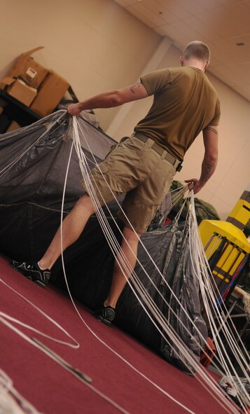 MOODY AIR FORCE BASE, Ga. -- Airman 1st Class Jack Benedict, 38th Rescue Squadron logistics flight aircrew flight equipment apprentice, pulls parachute lines together on a special operations vector parachute before packing it into a harness here May 10. Aircrew flight equipment is just one of the three shops that allow the special operations Airmen from the 38th RQS to be successful. (U.S. Air Force photo by Airman 1st Class Benjamin Wiseman/RELEASED)