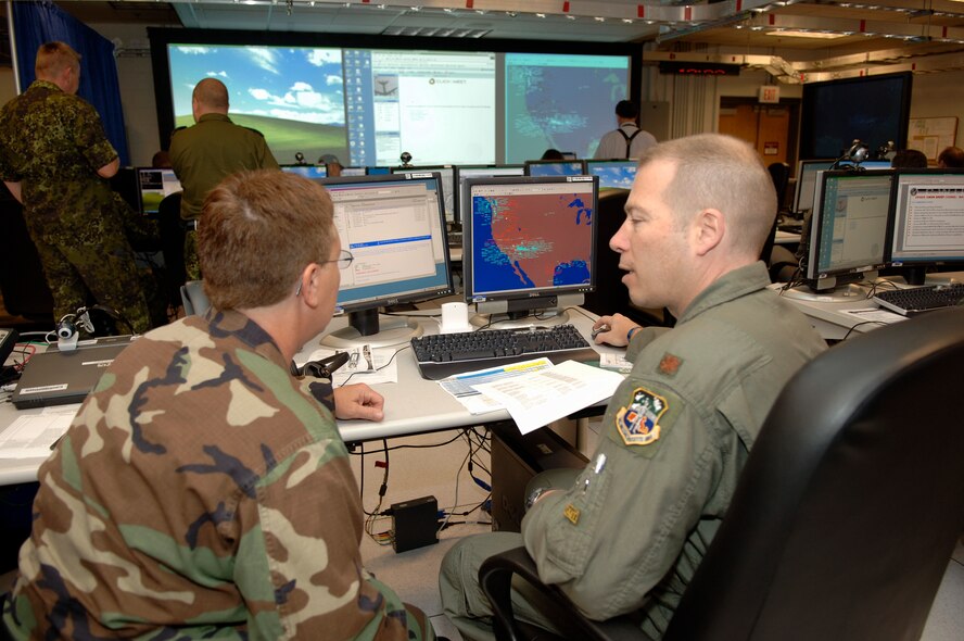 Airmen participating in the Coalition Warrior Interoperability Demonstration at Hanscom AFB in 2007 discuss one of the event's scenarios. CWID is an annual event that brings together the U.S. military with coalition partners, other government agencies and first responders to investigate and assess emerging C4ISR technologies. For CWID 2010, which begins June 14, Hanscom will host the Air Operations Center and be the lead Air Force site. (U.S. Air Force photo/Jan Abate) 