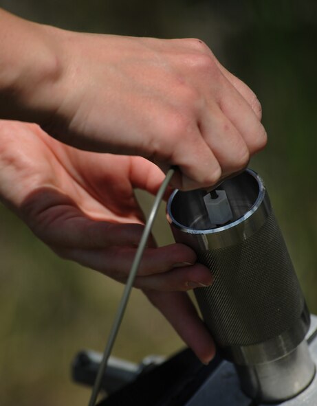 MOODY AIR FORCE BASE, Ga. -- Airman 1st Class Roxanna Shaw, 23rd Civil Engineer Squadron explosive ordnance disposal flight apprentice, attaches a shock tube to the back of the percussion actuated neutralizer device here May 12. A shock tube is a nonelectric initiation system that fires the PAN device and allows EOD members to detonate from a safe distance. (U.S. Air Force photo by Airman 1st Class Benjamin Wiseman/RELEASED)