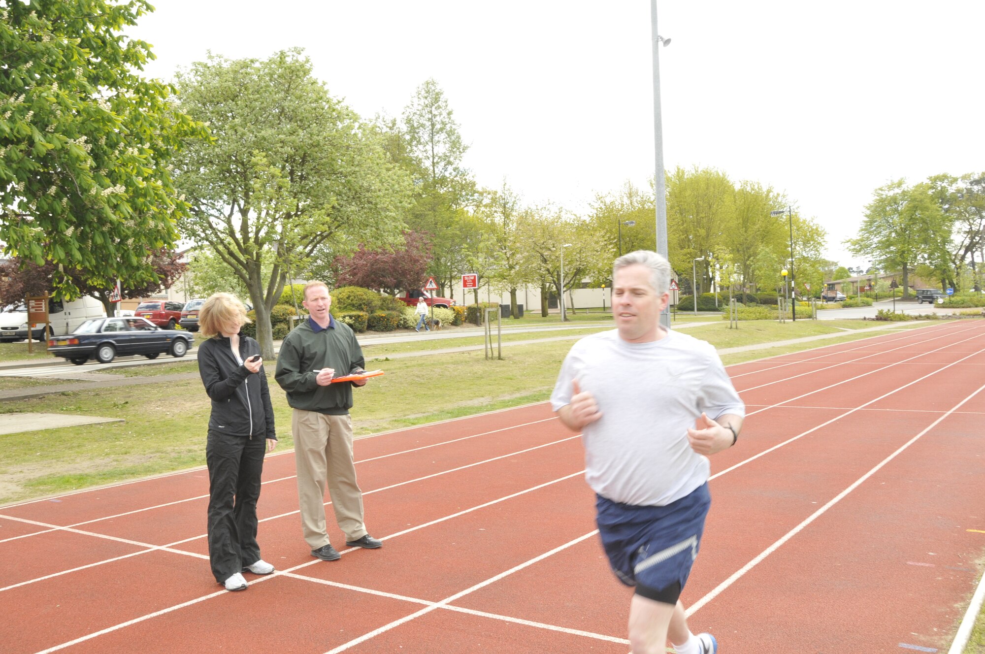 Jennifer Sibble and Rick Lyons, 48th Force Support Squadron fitness assessment cells, monitors Tech. Sgt. Christopher Campbell, 48th Fighter Wing Public Affairs NCO in-charge of internal operations, during his physical training test run May 12 at the RAF Lakenheath track. July 1 will mark the day when all physical training tests will be administered by FACs only. There will also be designated days and times for testing. (U.S. Air Force photo/Airman 1st Class Eboni Knox)