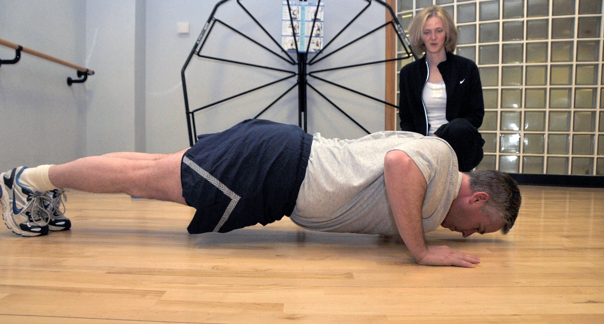 Jennifer Sibble, 48th Force Support Squadron fitness assessment cell, ensures Tech. Sgt. Christopher Campbell, 48th Fighter Wing Public Affairs NCO in-charge of internal operations, reaches the required 90-degree angle push-up position, while administering his physical training test at the RAF Lakenheath Fitness Center May 12. As of July 1, those testing must be in the Air Force issued PT gear while taking their test. (U.S. Air Force photo/Airman 1st Class Eboni Knox)