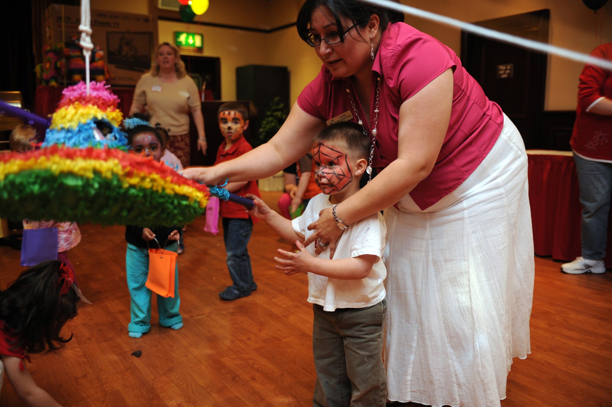 RAF MENWITH HILL, United Kingdom - Jacob Bishop takes a swing at a piñata, with the help of Cindy Biggerstaff, during a Cinco De Mayo celebration here May 8. The celebration was for the family members of deployed servicemembers of the 501st Combat Support Wing. At the event, all families received gift bags; four families won $50 AAFES gift certificates, and one family reveived a 42-inch flat screen TV, which was donated by AAFES. (U.S. Air Force photo/Staff Sgt. Brok McCarthy)