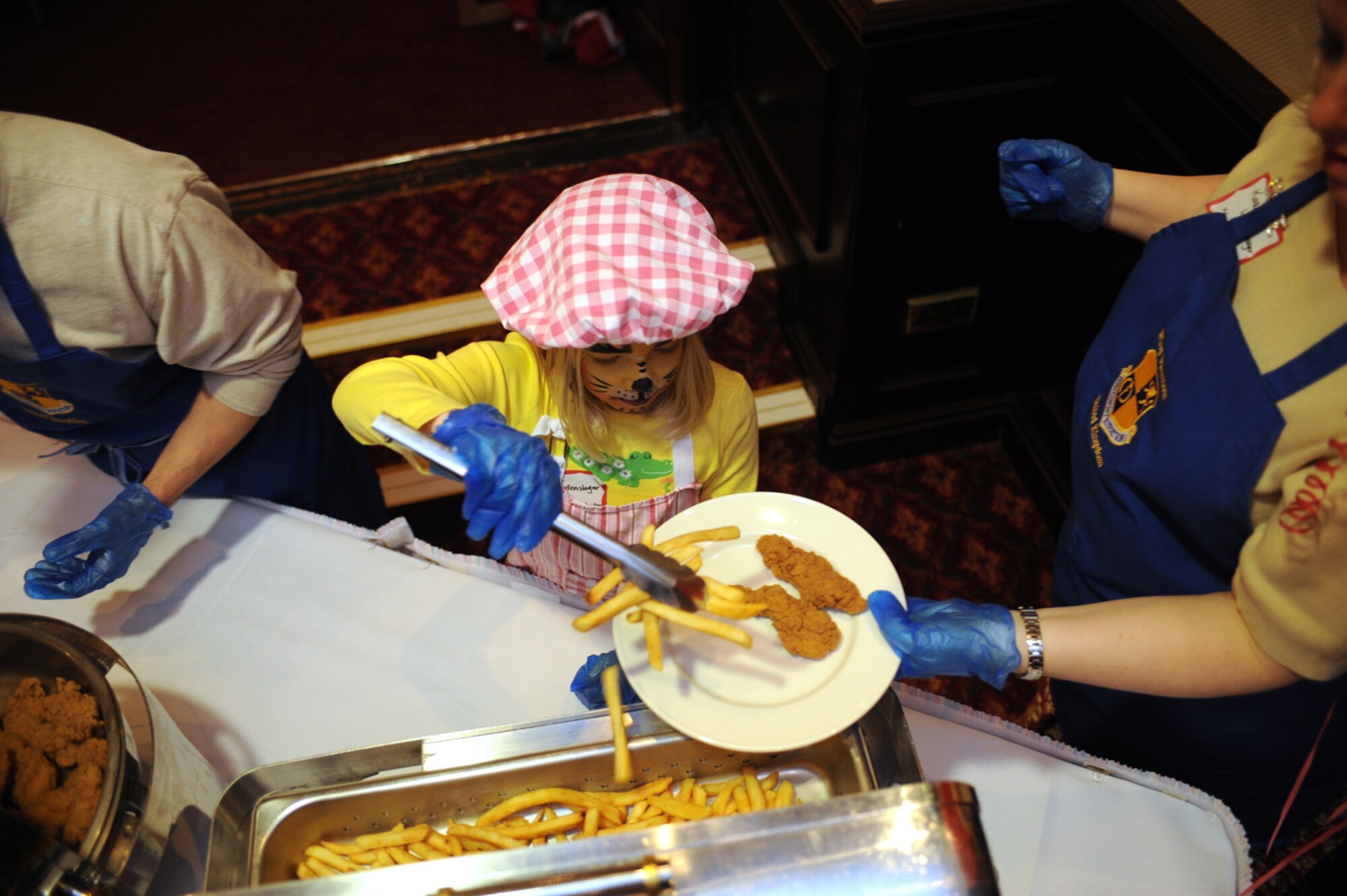 RAF MENWITH HILL, United Kingdom - During a Cinco De Mayo celebration for spouses of 501st Combat Support Wing deployed servicemembers, Claire Laudenslager, the youngest volunteer at the event, helps serve dinner at the Menwith Hill Community Club here May 8. At the event, all families received gift bags, four families won $50 AAFES gift certificates, and one family received a 42-inch flat screen TV, which was donated by AAFES. (U.S. Air Force photo/Staff Sgt. Brok McCarthy)