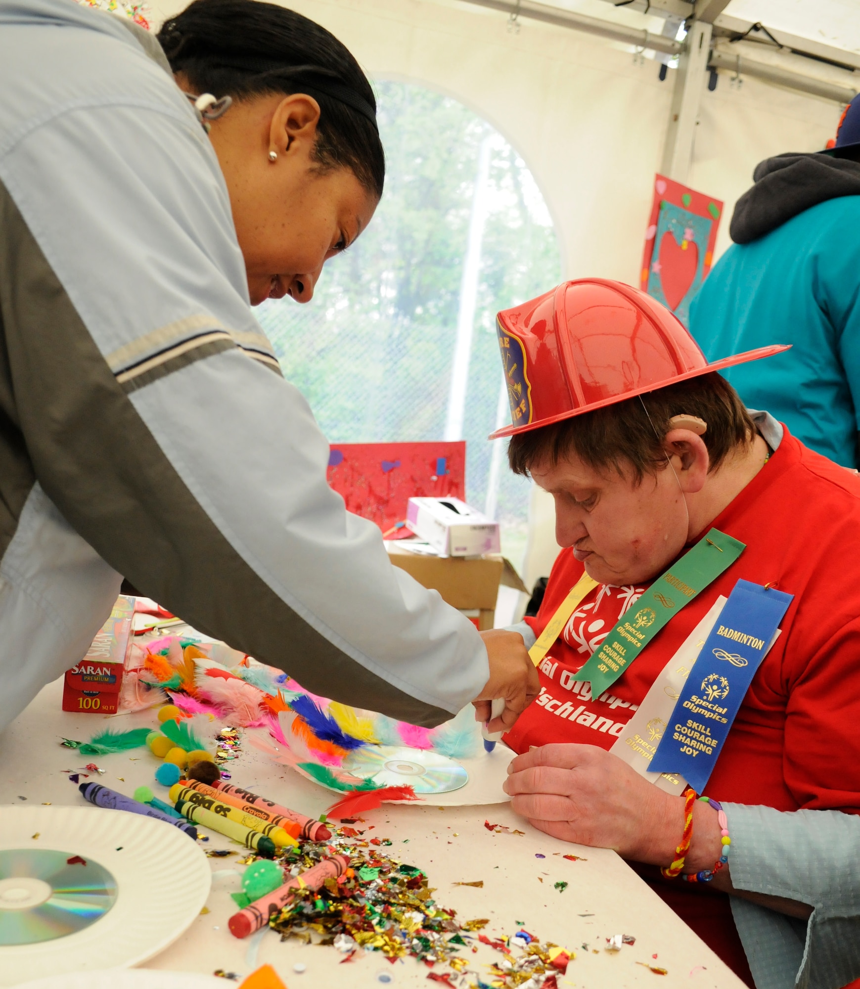 Tammie Honore, Ramstein Middle School teacher, assist an athlete in an arts and crafts section during the Special Olympics, Enkenbach-Alsenborn, Germany, May 12, 2010. Special Olympics is a worldwide event for children and adults with disabilities to build confidence and foster friendship. The Kaiserslautern Military Community hosted its 27th Annual Special Olympics for over 800 athletes. (U.S. Air Force photo by Airman 1st Class Brittany Perry)