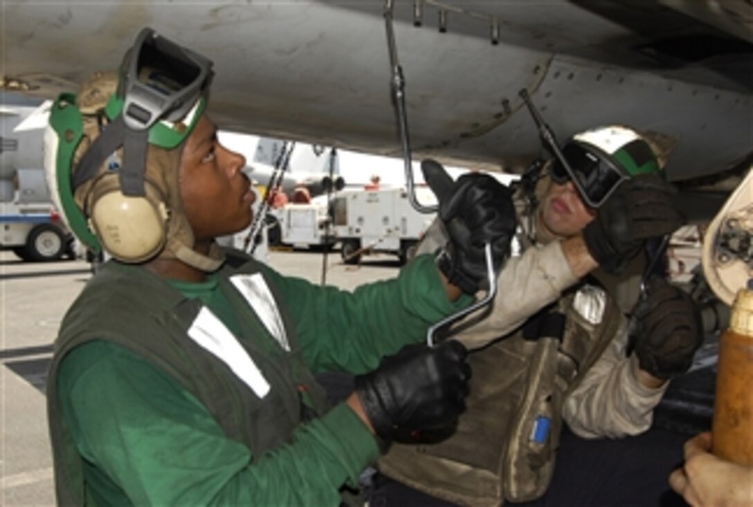 U.S. Navy Petty Officer 3rd Class Edward Effinger and Airman Christopher Estes perform routine maintenance on an F/A-18C Hornet aircraft aboard the aircraft carrier USS Dwight D. Eisenhower (CVN 69) underway in the north Arabian Sea on May 10, 2010.  The Eisenhower Carrier Strike Group was deployed as part of an ongoing rotation of forward-deployed forces supporting maritime security operations in the U.S. 5th Fleet area of responsibility.  