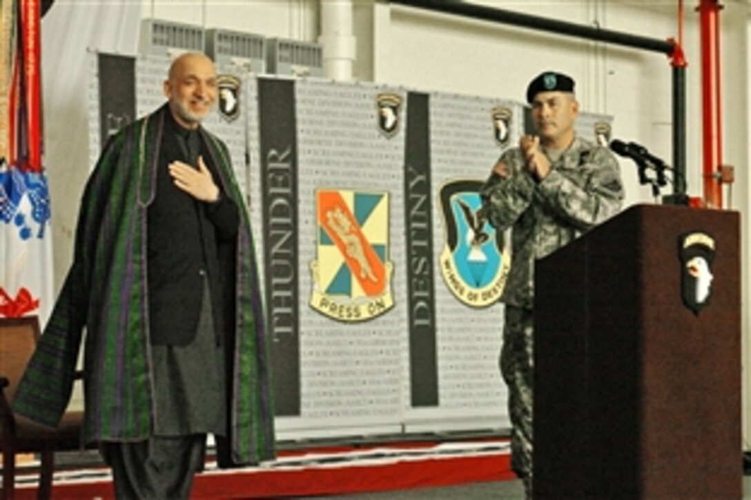 Afghanistan President Hamid Karzai places his hand over his heart in thanks to the soldiers of the 101st Aviation Division and their families as Army Maj. Gen. John F. Campbell, commanding general, 101st Airborne Division, applauds at Fort Campbell, Ky., May 14, 2010.  Karzai addressed the improved quality of life of Afghanistan due to the U.S. military's presence.