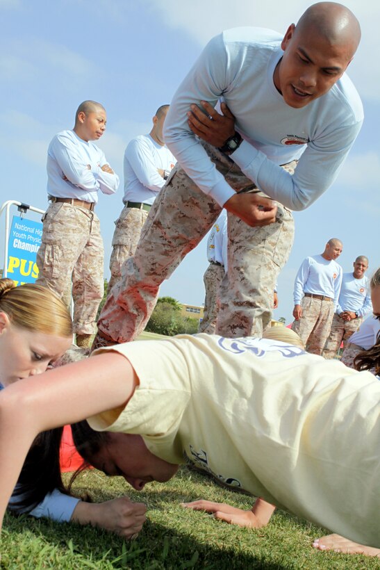 Staff Sgt. Abe V. Dominguez, Company C, Recruit Training Regiment, encourages Brittiny Bird, 16, Bethpage High School, Long Island, N.Y., during her remaining 59 push-ups at the 2010 Youth Physical Fitness Championship, May 14, at the depot’s track and soccer field. During the push-up event, participants were required to complete 60 push-ups within two minutes.