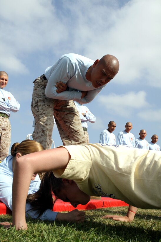 Staff Sgt. Abe V. Dominguez, Company C, Recruit Training Regiment encourages Brittiny Bird, 16, Bethpage High School, Long Island, N.Y., during the remaining 59 push-ups she did during the 2010 Youth Physical Fitness Championship May 14 at the depot’s track and soccer field. During the push-up event, participants were required to complete 60 push ups within 2 minutes.