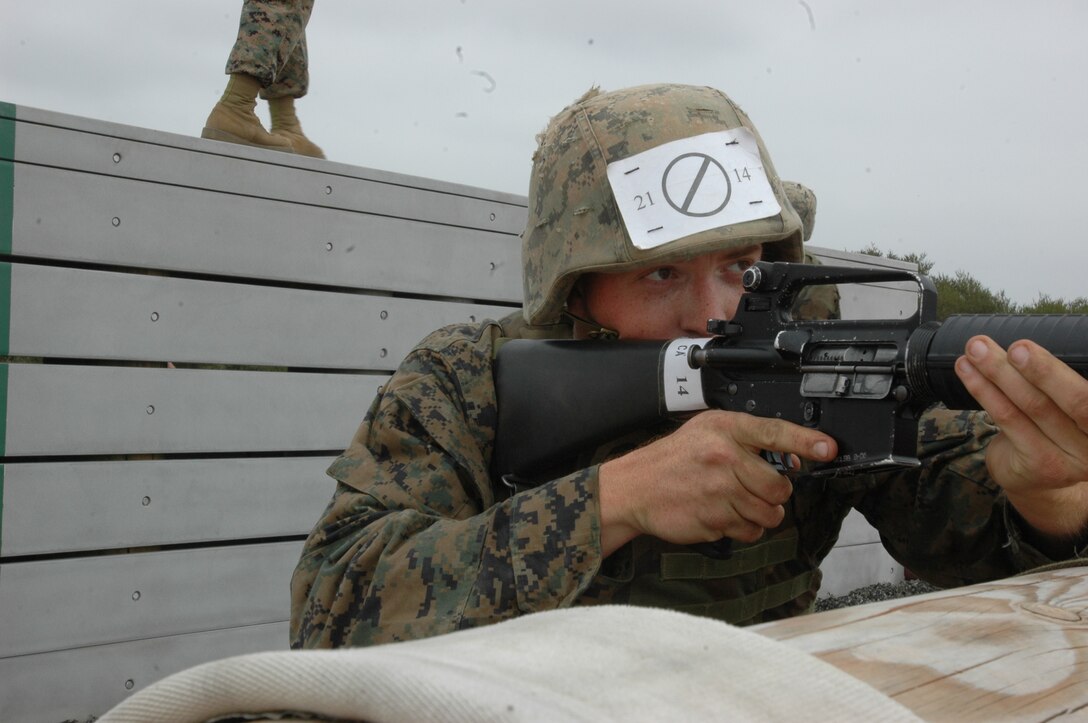 Pfc. Cassidy Mcomber, Platoon 2114, Company E, provides covering fire while his buddy climbs over the wall portion of the depot Obstacle Course, May 15. During the course, recruits were required to navigate various obstacles using teamwork.