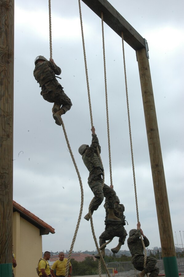 Company E Marines climb the rope under the supervision of their senior drill instructors during the depot Obstacle Course, May 15. The Marines climbed the rope in flak jackets and Kevlar helmets to complete their run of the course.