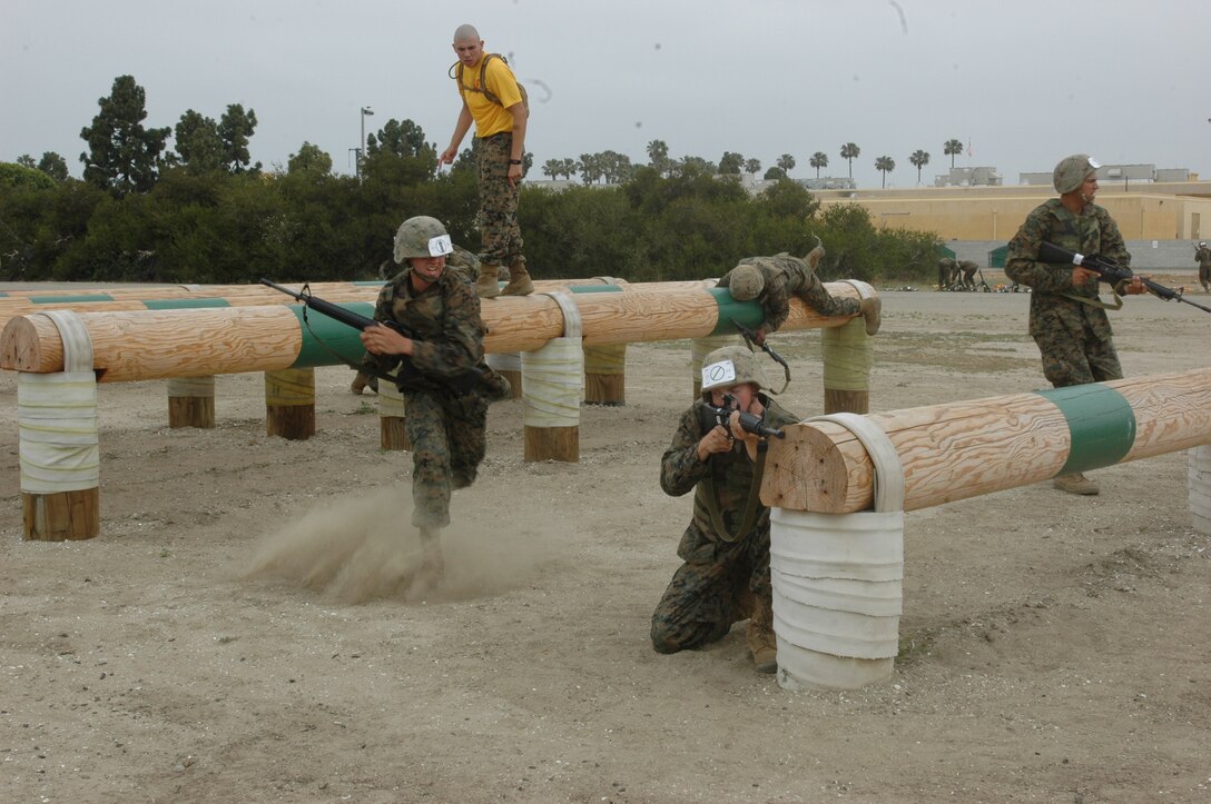 Company E Marines rush to get to the next cover position where their buddies await them on the depot Obstacle Course, May 15. The Marines had to traverse several logs before reaching their buddies.