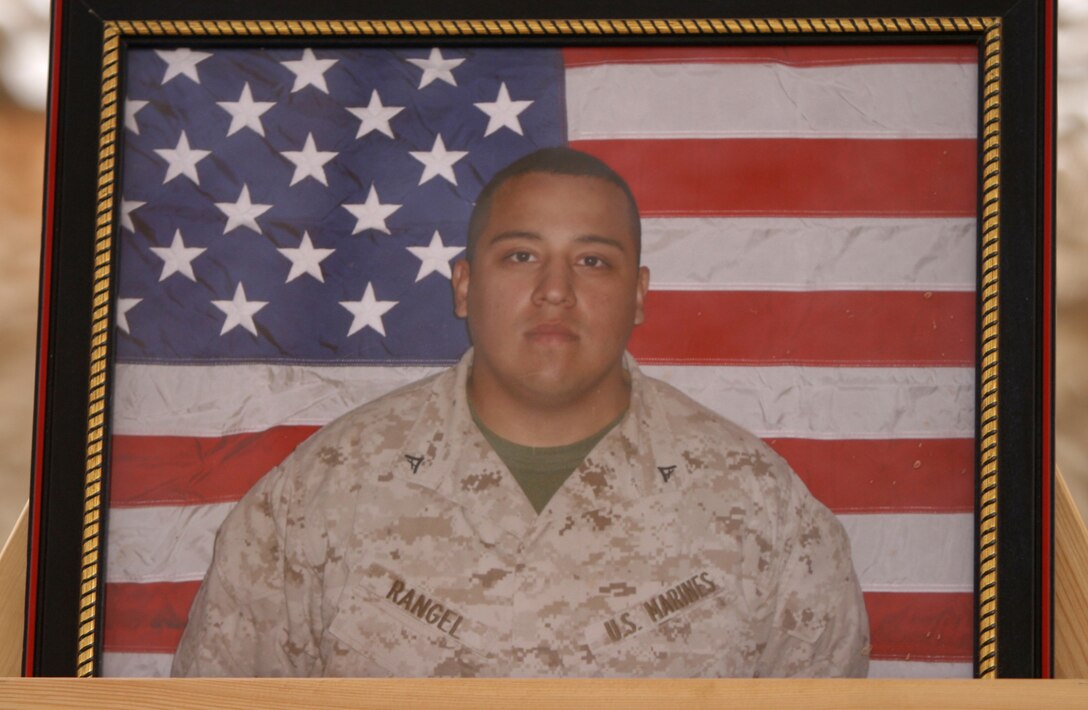 A photograph of Lance Cpl. Christopher Rangel stands during a service honoring his memory at Forward Operating Base Sher Wali, Marjah, Helmand province, Afghanistan, May 16, 2010. Rangel, a rifleman with 1st Platoon, India Company, 3rd Battalion, 6th Marine Regiment, passed away May 6 while conducting combat operations in support of Operation Moshtarak. The service included readings from the Bible, reflections from his fellow Marines, a three-round volley salute and a chance for the Marines and sailors at the event to pay their final respects to Rangel.