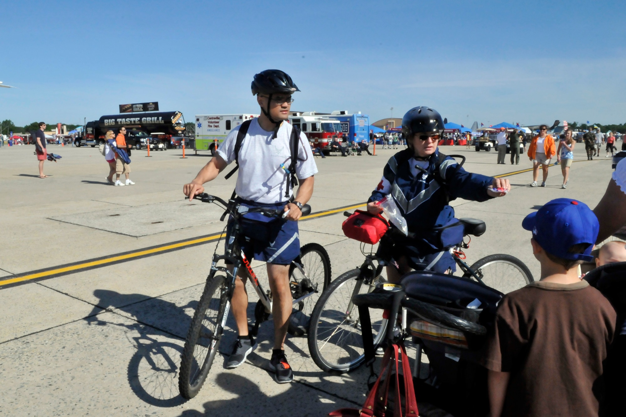 JOINT BASE ANDREWS, Md. - Senior Airman Daniel Sarao, a medical technician with the 779th Medical Operations Squadron (left) and Maj. Barbara Cain, a nurse with the 779 MDOS, hand out sunscreen while on bike patrol during the Joint Service Open House here May 15. JSOH offers interaction for all members of the joint service community and the public. (U.S. Air Force photo by Staff Sgt. Renae L. Saylock)