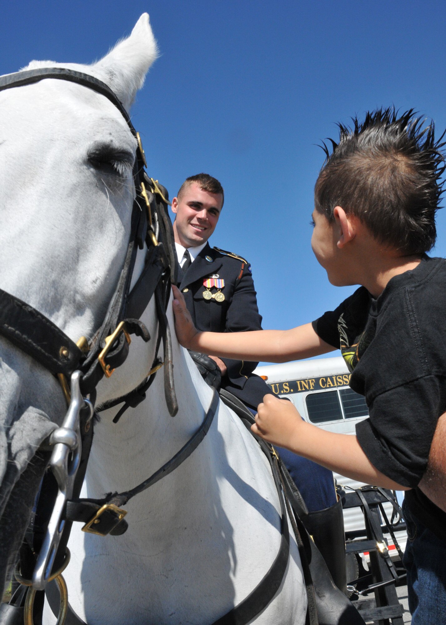 JOINT BASE ANDREWS, Md. – Army Specialist Patrick Shippert, 3rd Infantry Regiment “Old Guard” Caisson Platoon, looks down at Danny, 4-years-old, son of Jose Alvarez, local iron worker, while he pets his horse Babe on the flightline here May 15. JSOH offers an opportunity for the public to see military equipment from the Navy, Marines, Army, Air Force, and Coast Guard. (U.S. Air Force photo by Airman 1st Class Kat Lynn Justen)