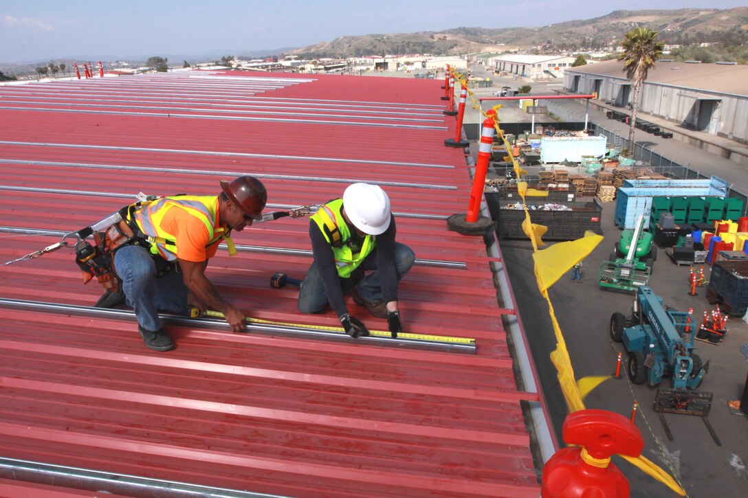 Edward J. Curione (left), and Eric M. Lieberman, both photovoltaic installers, Independent Energy Systems Inc., install a solar panel mounting system on the roof of Camp Pendleton’s Base Recycling Center, May 15. During the first Marine Corps Energy Summit in 2009, U.S. Marine Corps commandant, General James T. Conway, mandated every installation across the Corps increase renewable electric energy 25 percent by 2025.