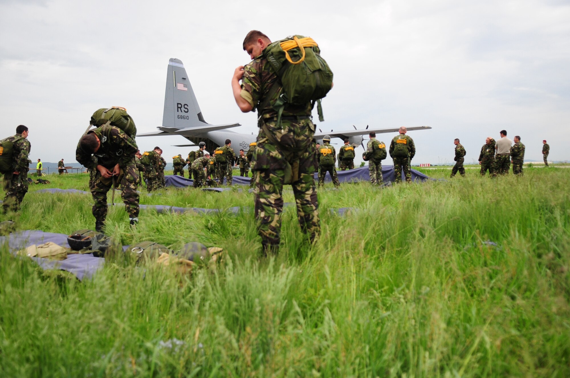 Romanian paratroopers don their static line parachutes in preparation to board and jump from a U.S. Air Force C-130J during exercise Carpathian Summer, Camp Turzii, Romania, May 13, 2010. Carpathian Summer 2010 was an exercise in which the Romanian Air Force invited members of the U.S. military to train with them on their soil and air space, to observe and practice, firsthand, operations in action. This exercise was designed to build partnerships between these nations in an effort to work together more efficiently during real world scenarios. (U.S. Air Force Photo by Staff Sgt. Jocelyn Rich)